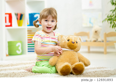 child girl playing doctor with plush toy at home child girl playing doctor with plush toy at home 12691893