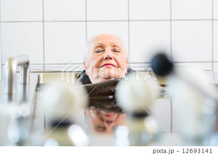 Senior woman enjoying mud bath alternative therapy 12693141