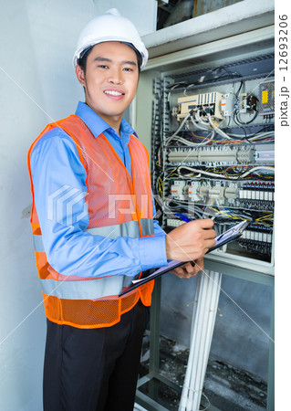 Asian Electrician at panel on construction site 12693206