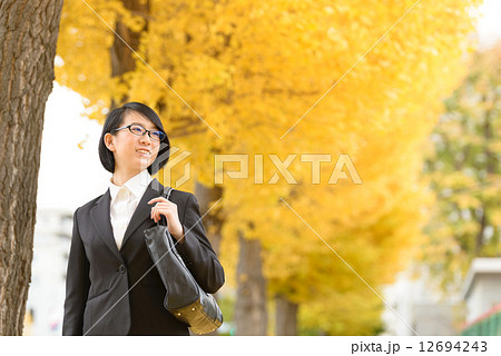 イチョウ並木を歩くビジネスウーマン 12694243