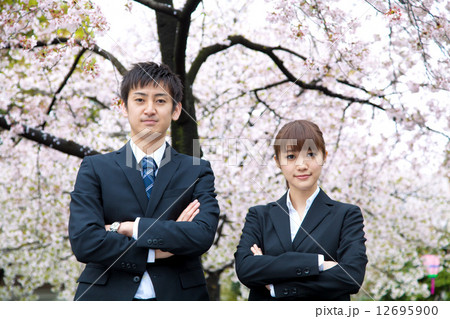 桜の前のスーツ姿の男女 12695900