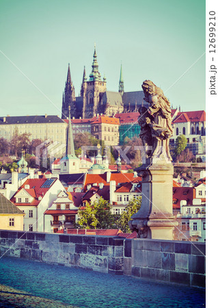 Statue on Charles Brigde against St. Vitus Cathedral in Prague 12699210