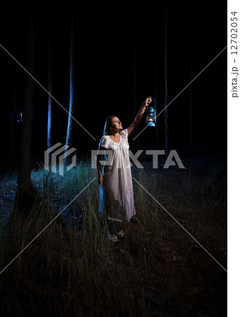 woman with gas lantern lighting up forest at night woman with gas lantern lighting up forest at night 12702054
