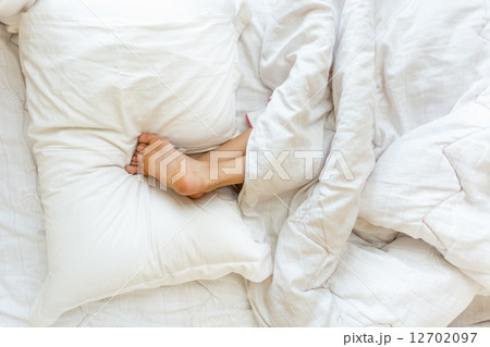 little girl sleeping upside down and holding feet on pillow 12702097