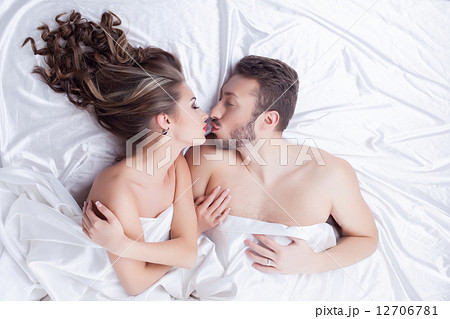 Beautiful lovers kissing while lying in bed Beautiful lovers kissing while lying in bed 12706781
