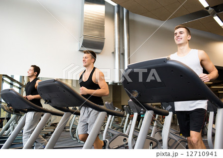 smiling men exercising on treadmill in gym 12710941