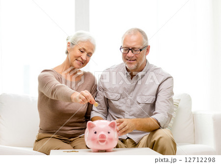 senior couple with money and piggy bank at home 12712298