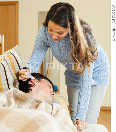 Girl dripping ear drops to man Girl dripping ear drops to man 12716116