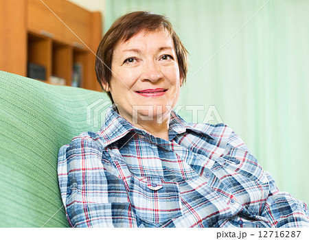 Portrait of happy senior woman relaxing in couch Portrait of happy senior woman relaxing in couch 12716287