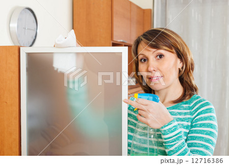 woman in green cleaning glass with detergent 12716386