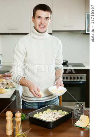 Guy cooking meat with cheese 12716567