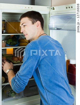 Handsome man looking for something in refrigerator Handsome man looking for something in refrigerator 12716608