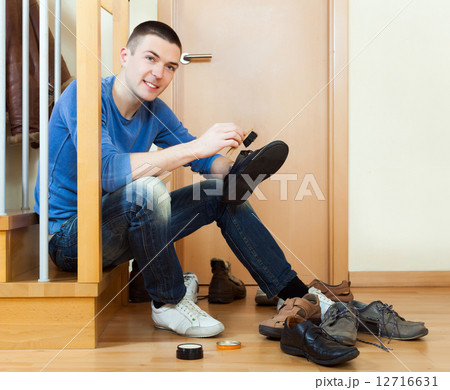 Happy man sitting on stairs and cleaning footwear Happy man sitting on stairs and cleaning footwear 12716631