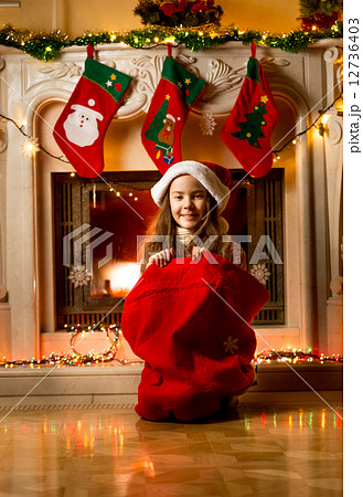 little girl sitting in Santa red bag at fireplace little girl sitting in Santa red bag at fireplace 12736403