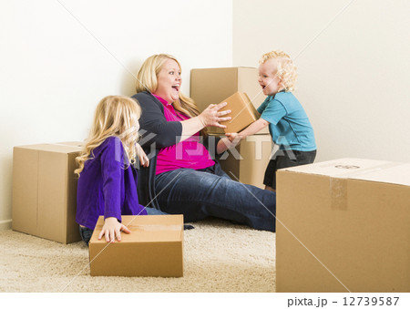 Young Family In Empty Room Playing With Moving Boxes Young Family In Empty Room Playing With Moving Boxes 12739587