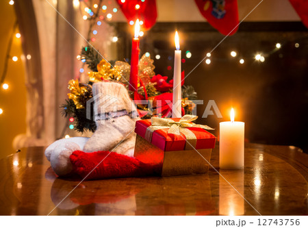candles, gift box and woolen sock placed on table against firepl 12743756