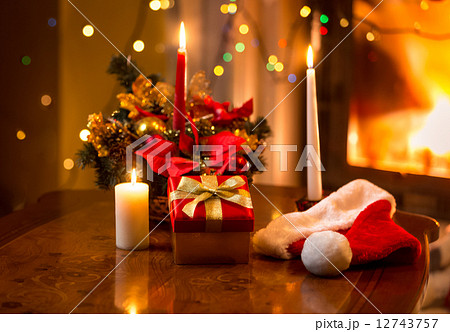 christmas photo of burning candles with giftbox against fireplac 12743757