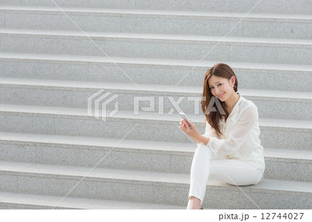 階段に座ってスマートフォンを持つ女性 階段に座ってスマートフォンを持つ女性 12744027