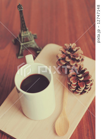 Black coffee and spoon on wooden tray with pine cone, retro filt 12747148