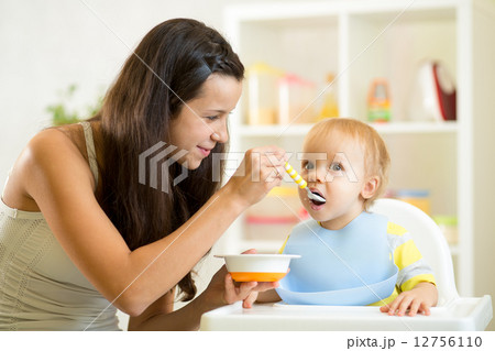 Mother spoon-feeding her child Mother spoon-feeding her child 12756110