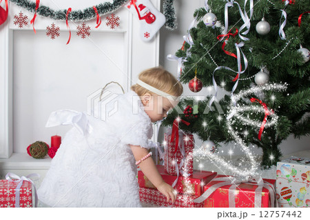 Cute little girl is looking for presents under Christmas New Year tree 12757442