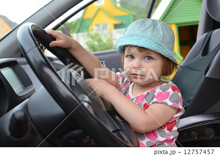 Cute little girl is sitting behind the wheel of a  car 12757457