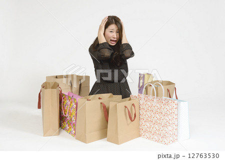 沢山の買い物袋の前で頭を抱える若い女性 沢山の買い物袋の前で頭を抱える若い女性 12763530