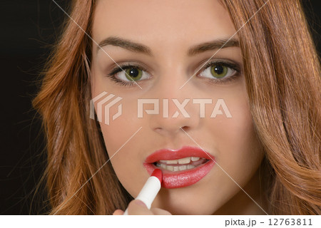 Woman applying lipstick Woman applying lipstick 12763811