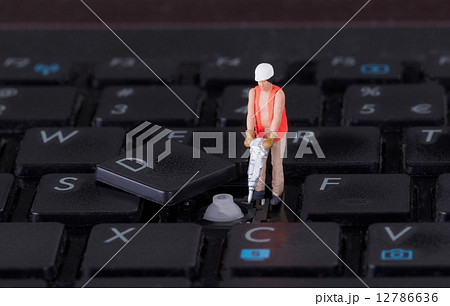 Miniature worker with drill working on keyboard 12786636