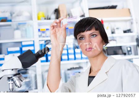 woman in a laboratory microscope with microscope slide in hand woman in a laboratory microscope with microscope slide in hand 12792057