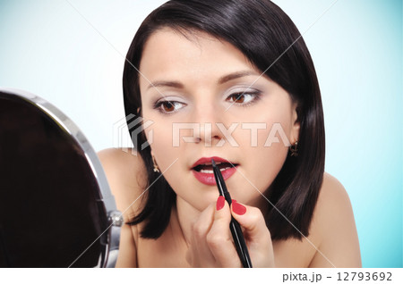 girl applying lipstick on lips girl applying lipstick on lips 12793692