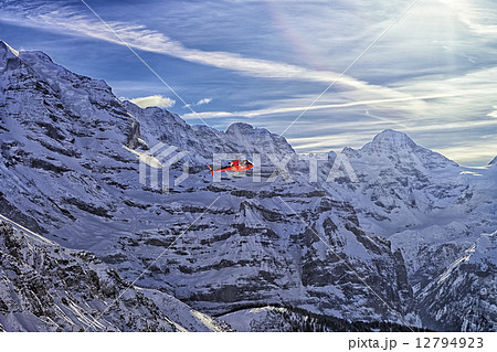 Red helicopter at swiss alps flying high 12794923