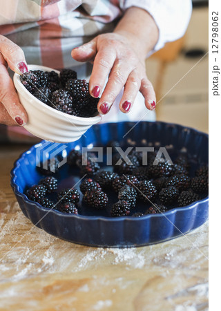 A woman pouring fresh blackberries into a dish. 12798062
