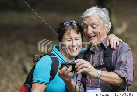 A mature couple looking at a digital camera, laughing. 12798085