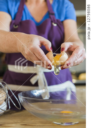 A woman at a kitchen table baking fairy cakes. 12798086