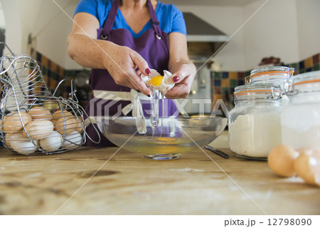 A woman at a kitchen table baking fairy cakes. 12798090