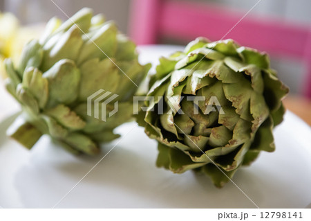 Two artichokes lying on a table. Two artichokes lying on a table. 12798141