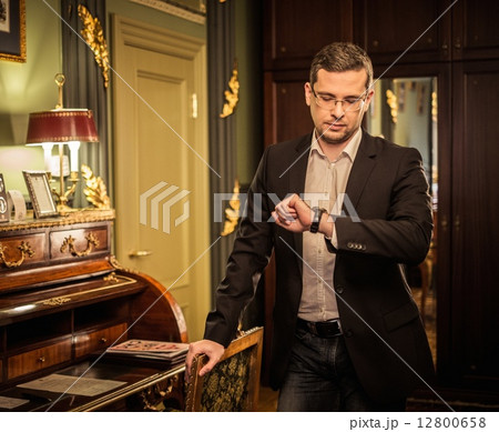 Middle-aged man looking at his wrist watch in luxury vintage style interior Middle-aged man looking at his wrist watch in luxury vintage style interior 12800658