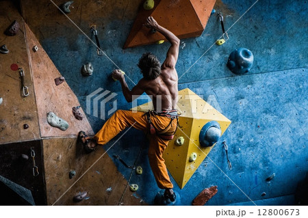 Muscular man practicing rock-climbing on a rock wall indoors 12800673