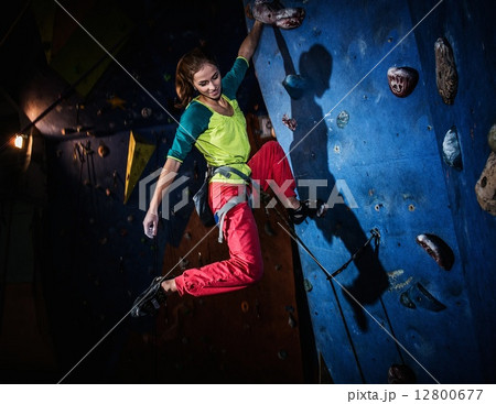 Young woman practicing rock-climbing on a rock wall indoors 12800677