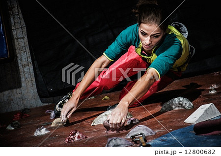 Young woman practicing rock-climbing on a rock wall indoors Young woman practicing rock-climbing on a rock wall indoors 12800682