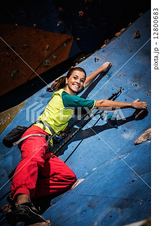 Young woman practicing rock-climbing on a rock wall indoors 12800683