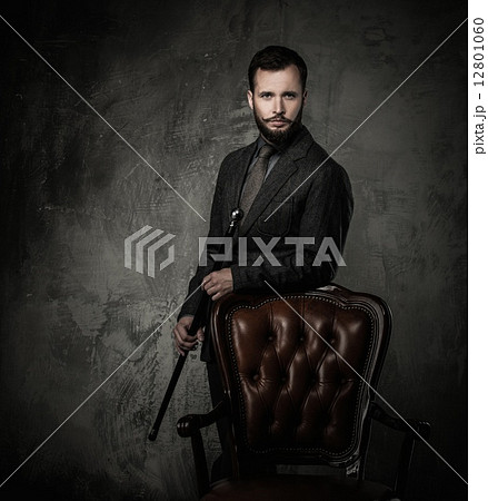 Handsome well-dressed man with stick standing near leather chair Handsome well-dressed man with stick standing near leather chair 12801060