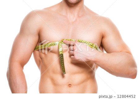 Man with a muscular torso uses measuring tape. 12804452