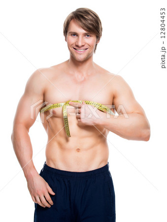 Young man with muscular torso uses measuring tape. Young man with muscular torso uses measuring tape. 12804453