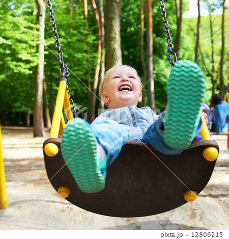 Happy little blond boy having fun on a swing. 12806215