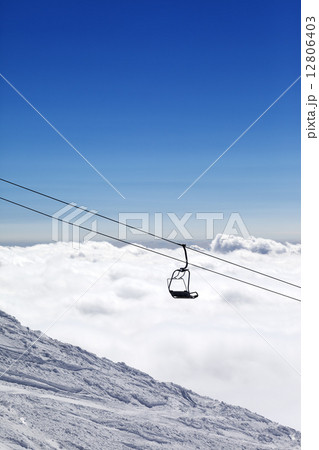 Ski slope, chair-lift and mountains under clouds Ski slope, chair-lift and mountains under clouds 12806403