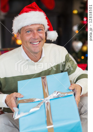 Smiling man in santa hat opening a gift Smiling man in santa hat opening a gift 12838501