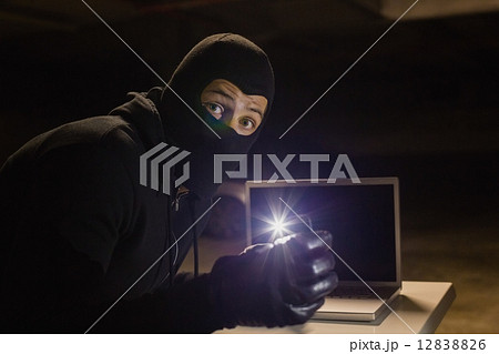 Robber looking at camera while making light with his phone Robber looking at camera while making light with his phone 12838826