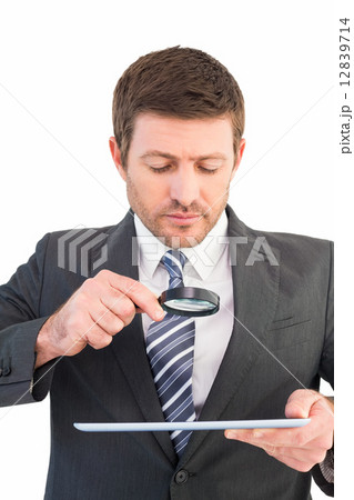 Businessman looking at tablet with magnifying glass 12839714